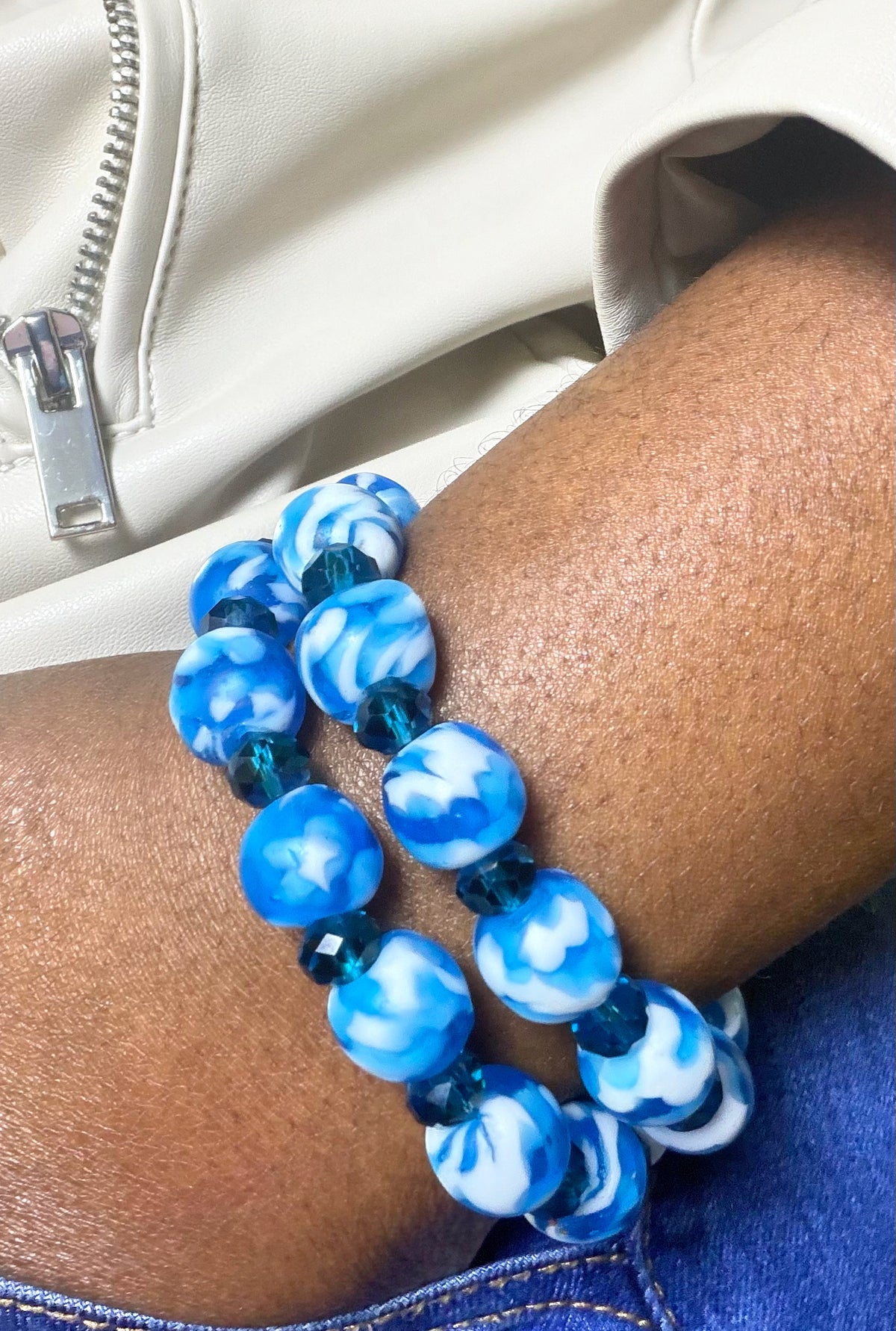 Blue and white beaded bracelet on a wrist with a neutral background